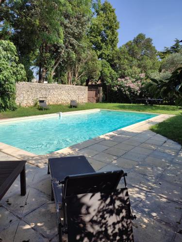 une chaise assise à côté d'une piscine dans l'établissement Le mas Roc'amour, à Roquemaure