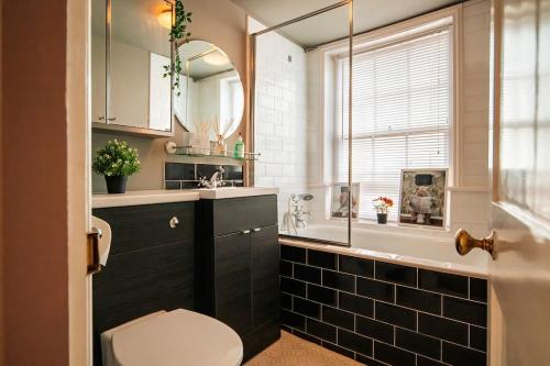 a bathroom with a toilet and a sink and a mirror at Seaside Bliss: Period Home, Games Room, Pool Table & Hot Tub in Margate