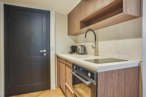 a small kitchen with a sink and a black door at Apart hotel Centre de Paris by Studio prestige in Paris