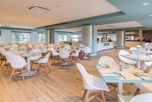 a dining room with tables and white chairs at Ponient Pirámide Salou by PortAventura World in Salou