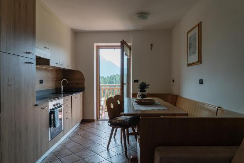 uma cozinha com uma mesa e uma cozinha com uma varanda em Tobià Brujà em Vigo di Fassa