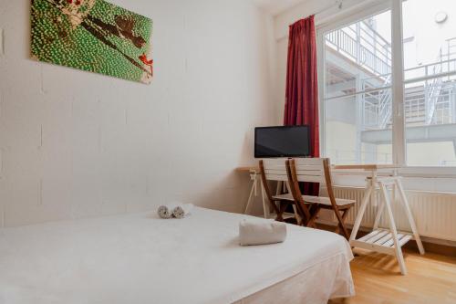 een kamer met 2 bedden, een bureau en een televisie bij Dupre Cosy Residence in Brussel