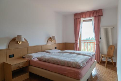 a bedroom with a large bed and a window at Tobià Brujà in Vigo di Fassa