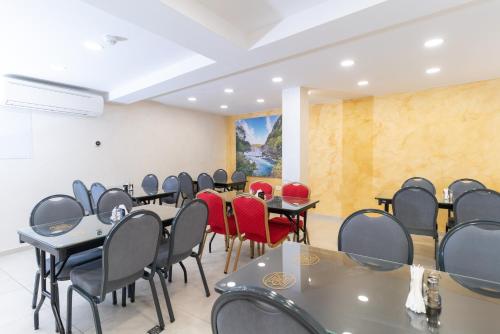 Ornament Hotel and Apartments في سراييفو: قاعة اجتماعات مع طاولات وكراسي حمراء