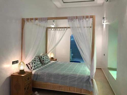 1 dormitorio con cama con dosel y ventana en Kasbah ben hamou, en Nkob
