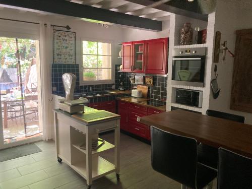 eine Küche mit roten Schränken und einem Holztisch in der Unterkunft Lou camin dou cagnard in Méthamis