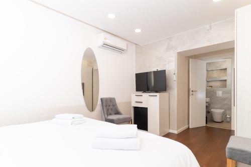 a white room with a bed and a mirror at Ornament Hotel and Apartments in Sarajevo