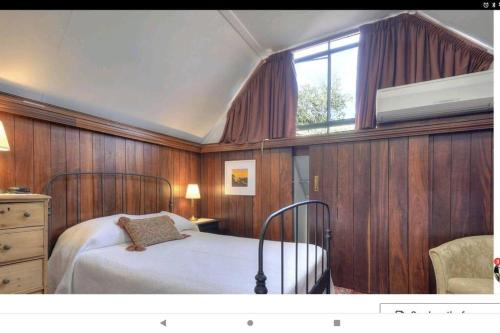 um quarto com uma cama com paredes de madeira e uma janela em Snow-white's 2 bedroom City heart Cottage in Perth 6000 em Perth