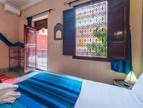 馬拉喀什的住宿－里亞德托德拉旅館，一间卧室设有一张床和一个彩色玻璃窗