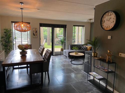 a living room with a table and a clock on the wall at Wellness Bosboerderij de Goudsberg met hottub en sauna in Lunteren