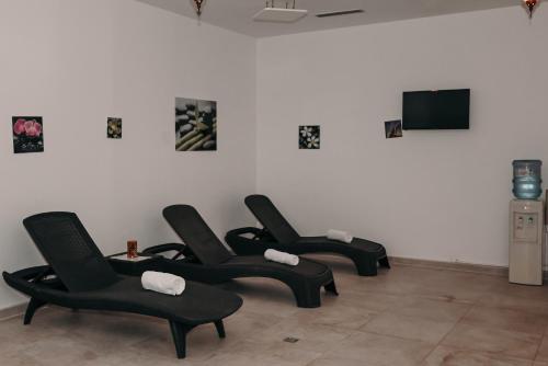 four black chairs in a room with a tv at Boutique Hotel Ukus in Tešanj