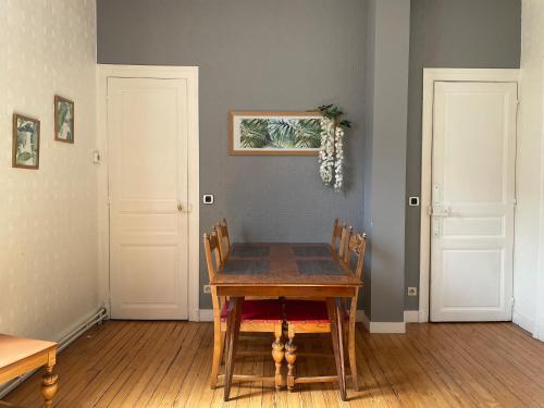 une salle à manger avec une table en bois et deux portes blanches dans l'établissement L Ensorcel Mans, séjour magique en coeur de ville, au Mans