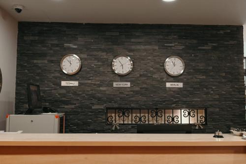 a wall with four clocks on a brick wall at Boutique Hotel Ukus in Tešanj