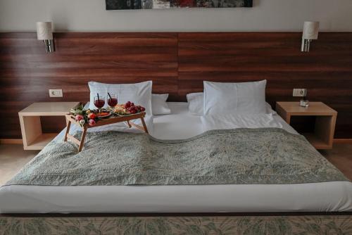 a large bed with a tray of wine glasses on it at Boutique Hotel Ukus in Tešanj