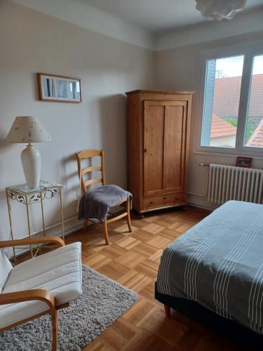een slaapkamer met een bed, een stoel en een raam bij Entre Loire et canal in Briare
