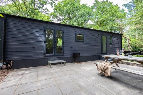 a black cabin with a picnic table in front of it at Prachtig chalet in de bossen in Nunspeet