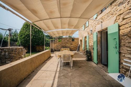 un patio con mesa y sillas bajo un techo en Petit Mas au calme proche centre, en Bagnols-sur-Cèze