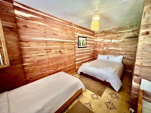 two beds in a room with wooden walls at Dar l'eau Vive in Bine el Ouidane
