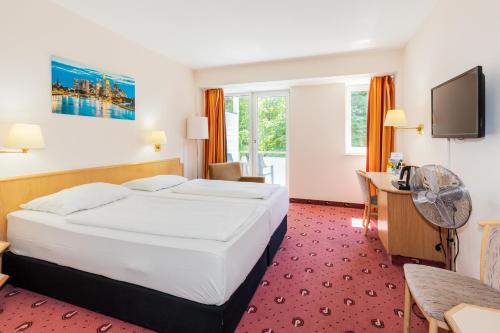 a hotel room with a bed and a desk at Parkhotel Frankfurt Airport in Hattersheim