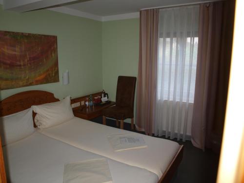 a bedroom with a bed and a chair and a window at Gästehaus Engelgasse Herzogenaurach in Herzogenaurach