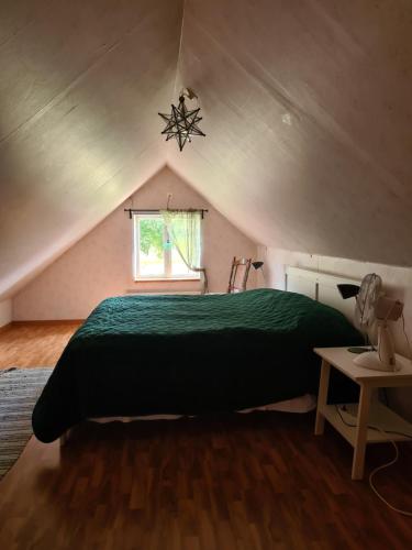 Un dormitorio con una cama verde en un ático en Hjälmarödsgård en Kivik