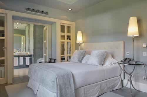 a bedroom with a large white bed and a bathroom at Hotel Iturregi in Getaria