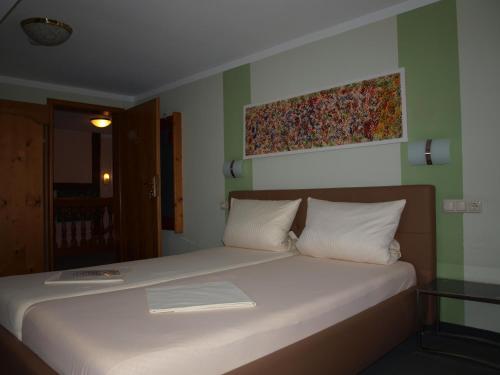 a bedroom with a bed with white sheets and a painting on the wall at Gästehaus Engelgasse Herzogenaurach in Herzogenaurach