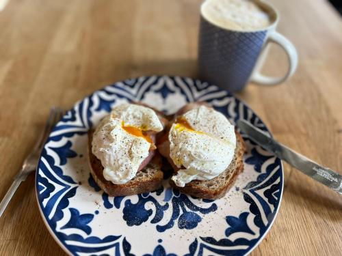dos huevos en un plato con una taza de café en Eydon B&B en Daventry