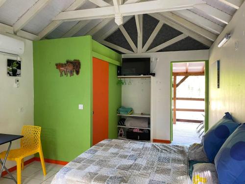 a bedroom with green and orange walls and a bed at Bungalow charmant à Petit-Bourg avec jardin privé in Petit-Bourg
