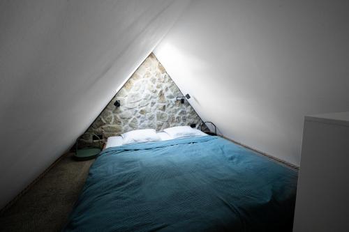 um quarto com uma cama azul e uma parede de pedra em Apartman 19 em Banská Štiavnica