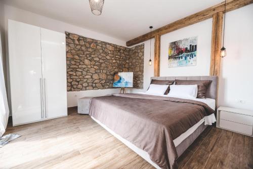 a bedroom with a large bed and a stone wall at Beachfront Villa Grace with heated rooftop pool in Jadranovo