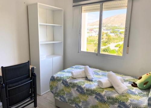 a bedroom with a bed with a window and a chair at Cozy apartment Benidorm Poniente 5 min from the beach in Benidorm