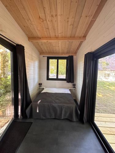 - un lit dans une petite chambre avec 2 fenêtres dans l'établissement Tiny house, à Saint-Lyphard