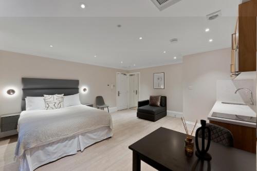 a white bedroom with a bed and a desk at Cleveland Residences Paddington in London