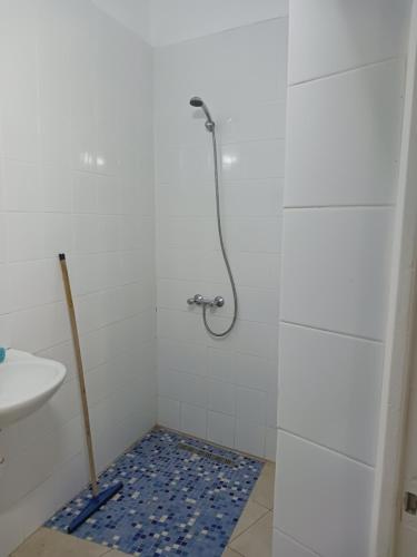 y baño con ducha y suelo de baldosa azul. en Appartement Fethia, en Houmt El Souk