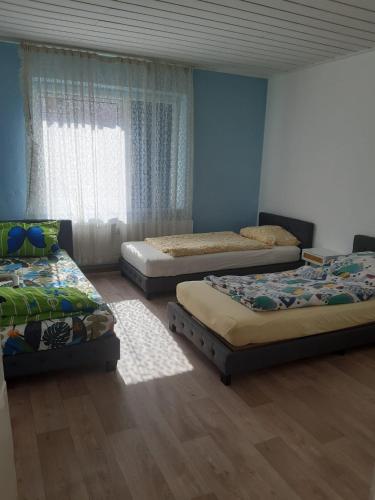 three beds in a room with blue walls and wooden floors at worker-flat in Gelsenkirchen