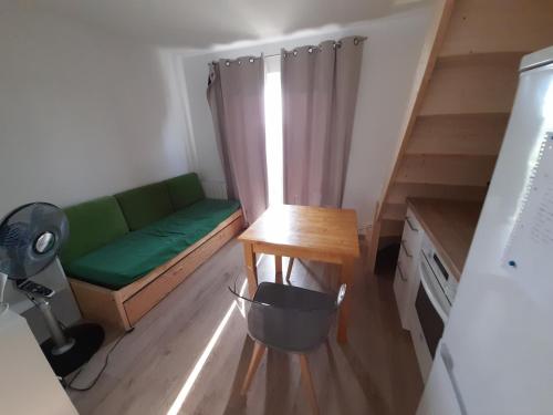 ein kleines Zimmer mit einem grünen Sofa und einem Tisch in der Unterkunft Le Mialan t1 à la campagne à 10 minutes de Valence in Saint-Péray