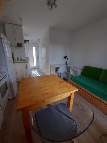 ein Wohnzimmer mit einem Holztisch und einer grünen Couch in der Unterkunft Le Mialan t1 à la campagne à 10 minutes de Valence in Saint-Péray