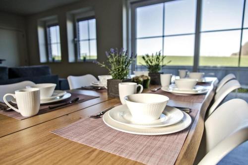 a wooden table with white cups and plates on it at Les Petits Sablens in Grandmetz