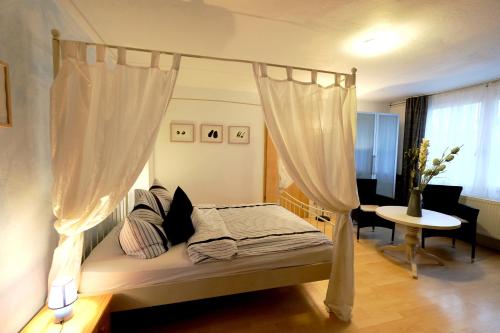 a bedroom with a canopy bed with white curtains at Luxus-Ferienhaus auf Reiterhof ART.Quartier in Velgast