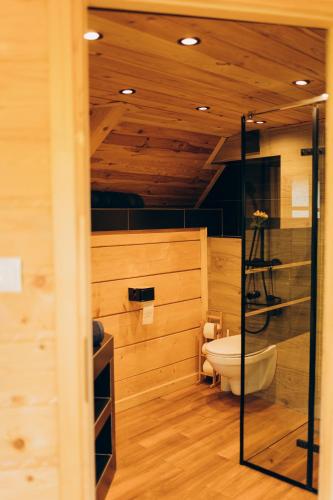 a bathroom with a toilet and a glass shower at Osada Poli - Domek Panoramiczny nad Narwią z Prywatną Balią i Hydromasażem in Łachy