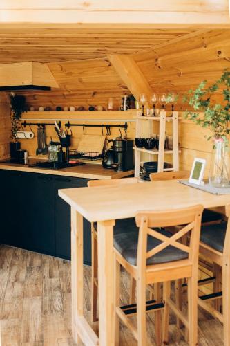 a kitchen with a wooden table and chairs at Osada Poli - Domek Panoramiczny nad Narwią z Prywatną Balią i Hydromasażem in Łachy