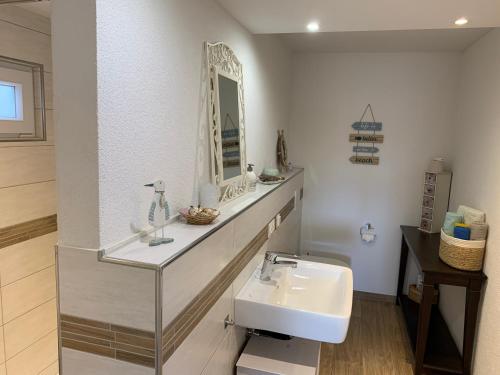 a white bathroom with a sink and a mirror at Am Sonnenhang in Hilzingen