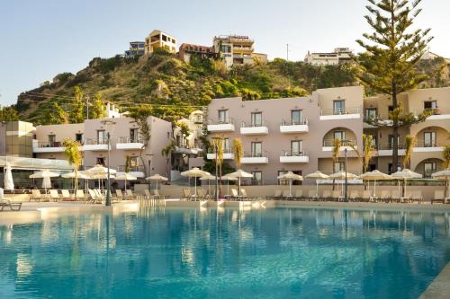a hotel with a large swimming pool with umbrellas at Porto Platanias Village Resort in Plataniás
