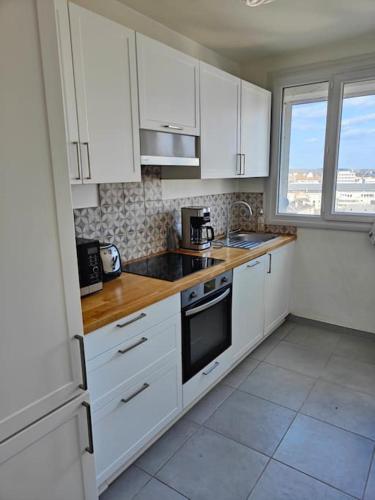 une cuisine blanche avec des armoires blanches et une fenêtre dans l'établissement Superbe appartement lumineux avec vue imprenable, à Tours