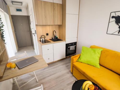 a living room with a yellow couch and a table with a laptop at Sander Apartments in Kraków