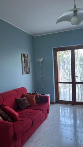 ein rotes Sofa im Wohnzimmer mit Fenster in der Unterkunft An Eye on Taormina in Letojanni