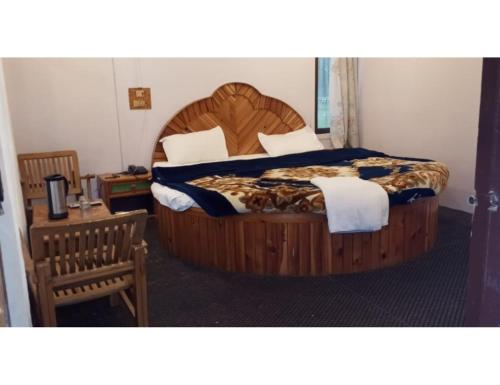 1 dormitorio con 1 cama grande de madera en una habitación en Hotel Prem Rose, Pahalgam, en Pahalgām