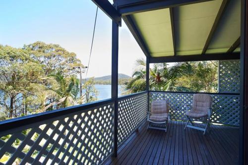 two chairs on a porch with a view of the water at Riviera on Hawkesbury An island style escape in Bar Point