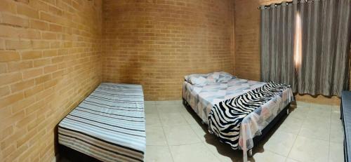 1 dormitorio con 2 camas y pared de ladrillo en GV Apartamentos-2qt-area central nobre- ar cond- en Governador Valadares